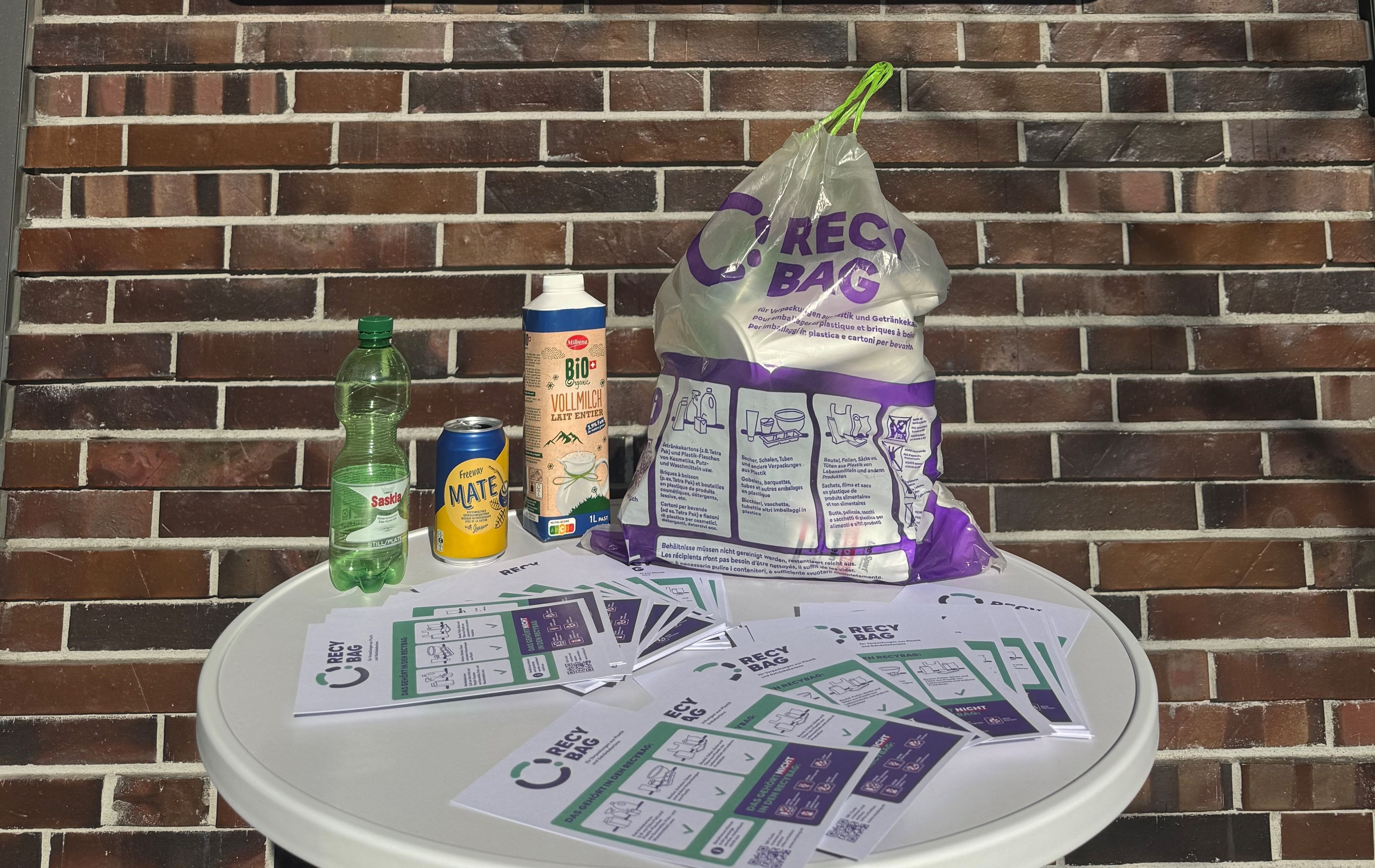 Infotisch vor einer Lidl-Filiale mit dem Recybag-Sammelsack, verschiedenen recycelbaren Verpackungen und Flyern zum Sammelsystem.