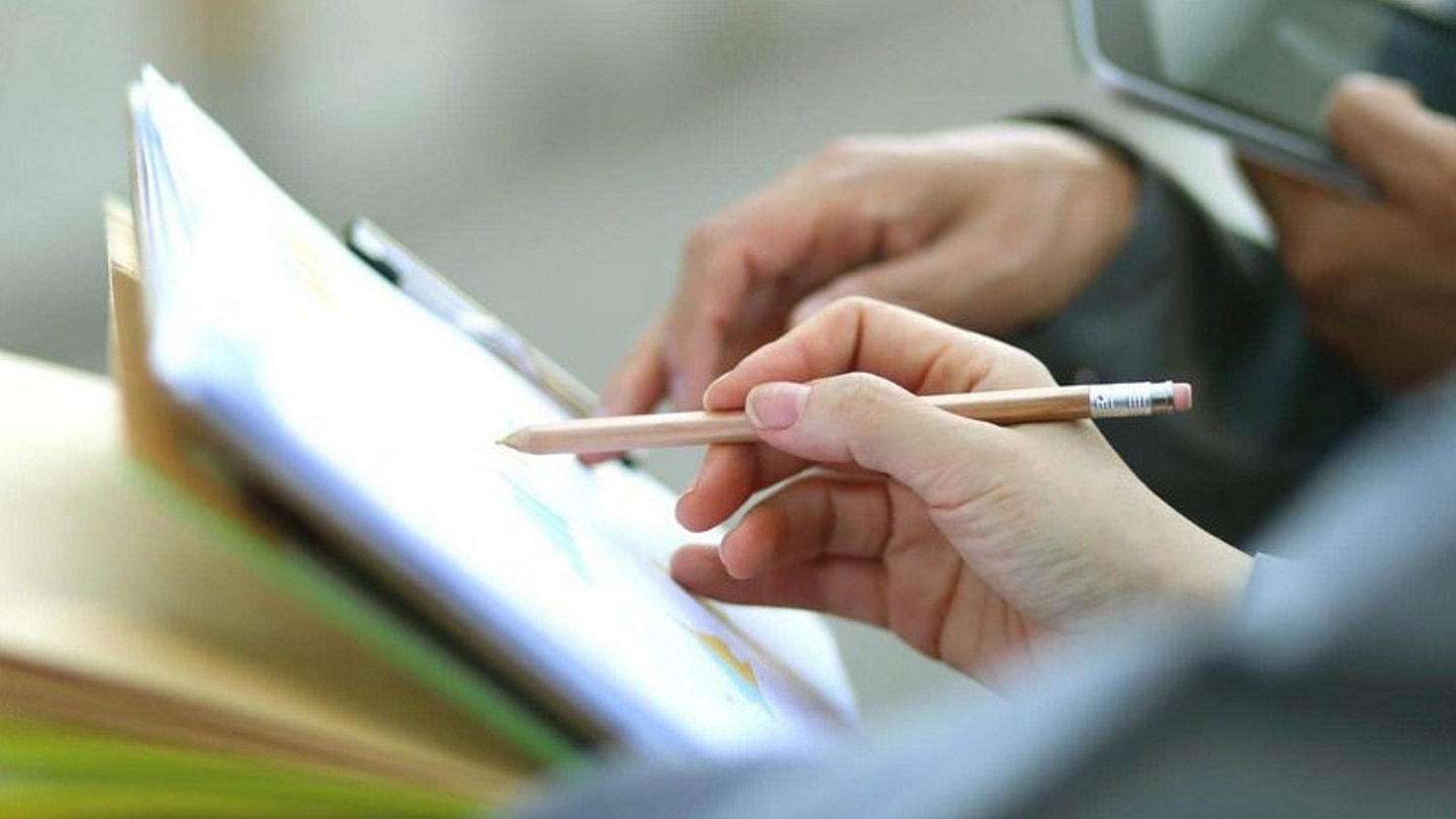 Mani con penna che mostrano diagrammi di audit sociale.