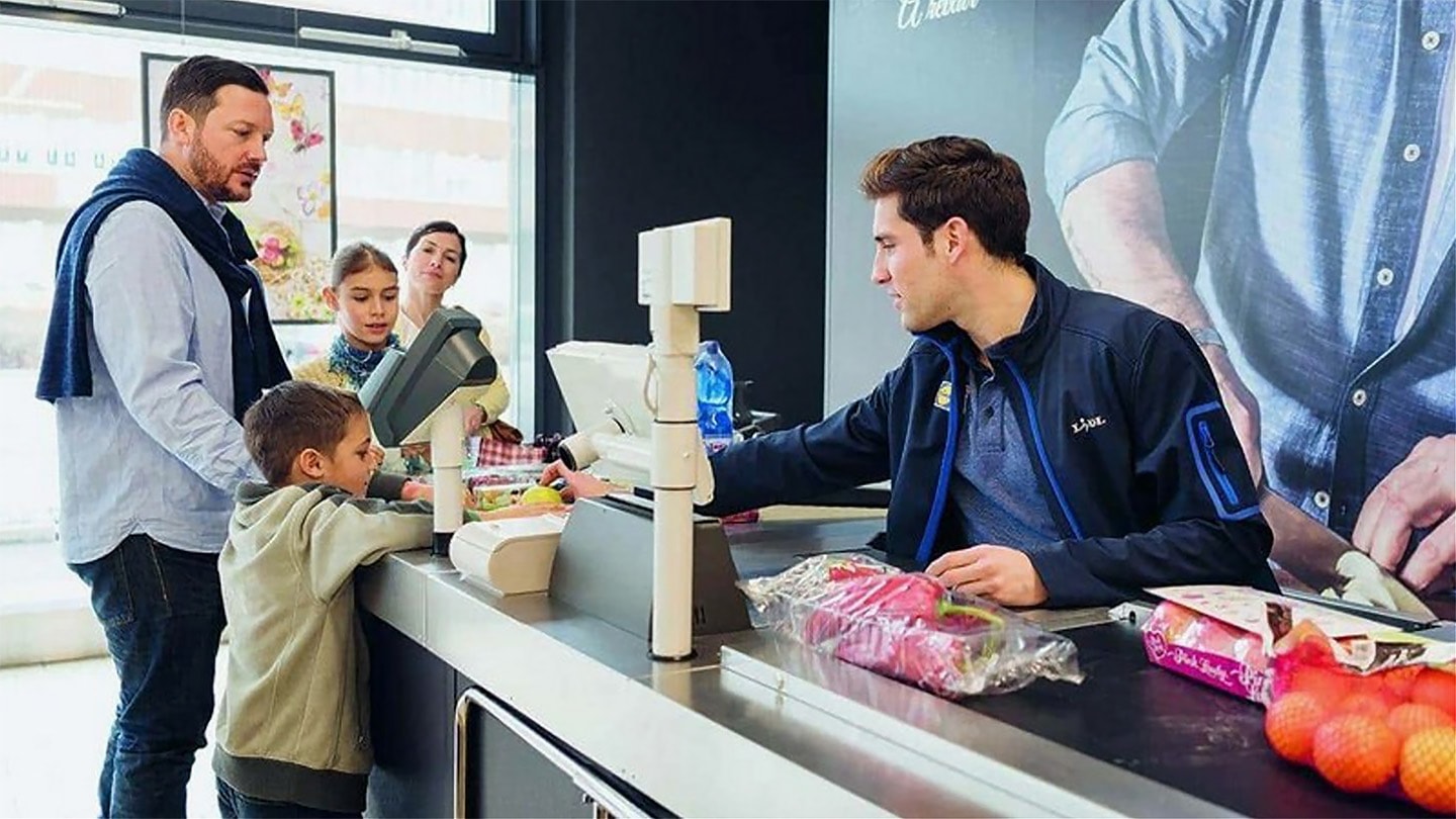 Un employé de Lidl sert une famille à la caisse.