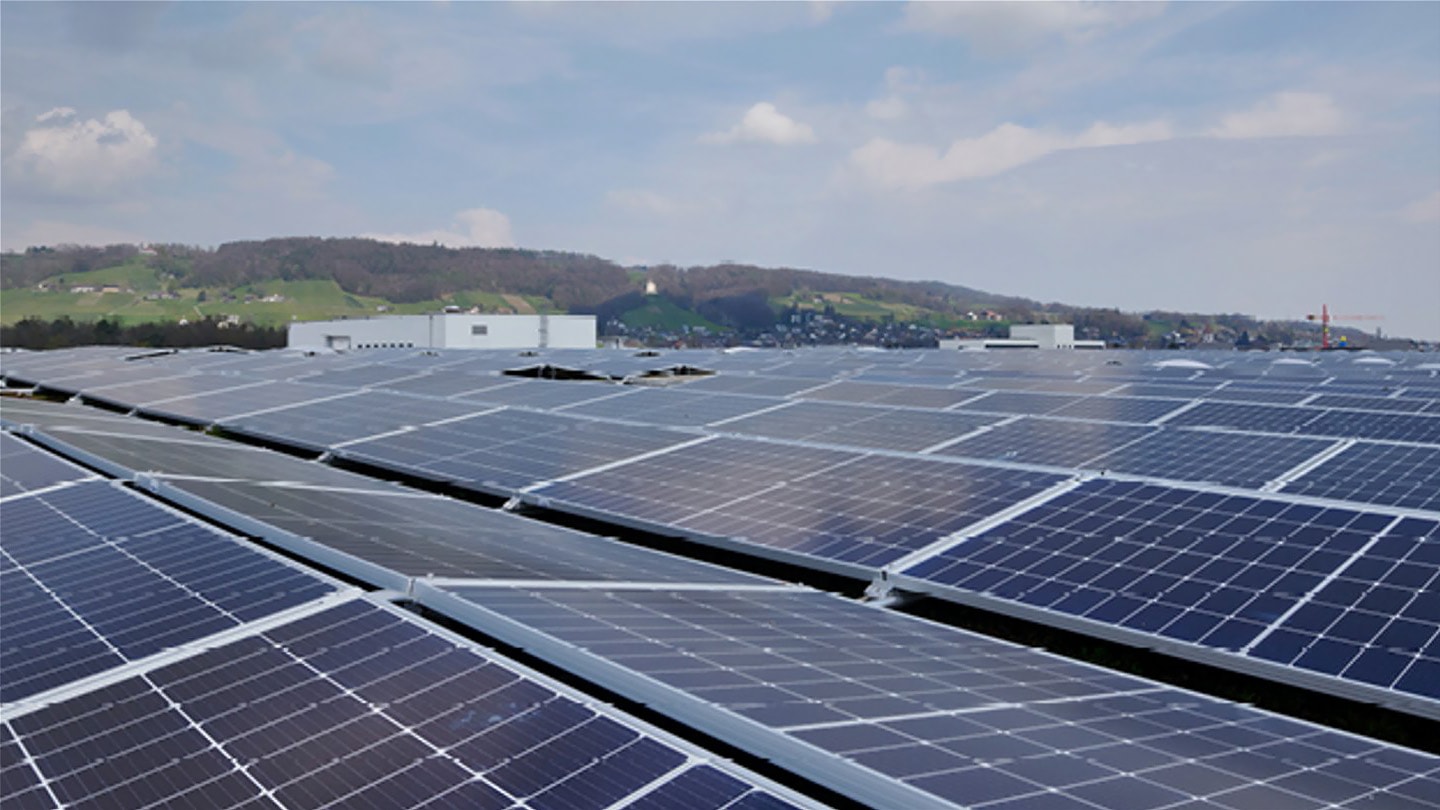 Solarpanel auf Dach, im Hintergrund schweizer Hügel.