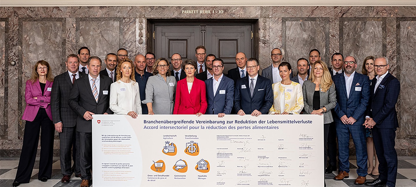 Plusieurs personnes, dont Simonetta Sommaruga, tiennent une affiche présentant l'accord visant à réduire les pertes alimentaires.