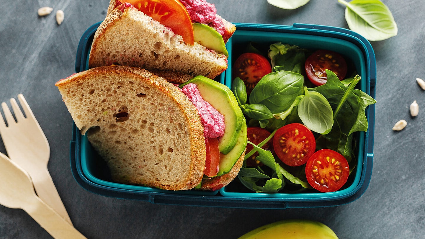 Ausgewogener Znüni mit Sandwich, Avocado, Tomate und Basilikum für Kinder.