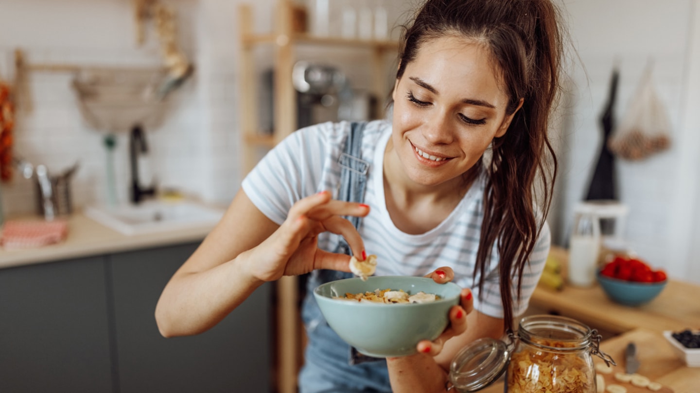 Junge Frau bereitet sich ein gesundes Müesli zu.