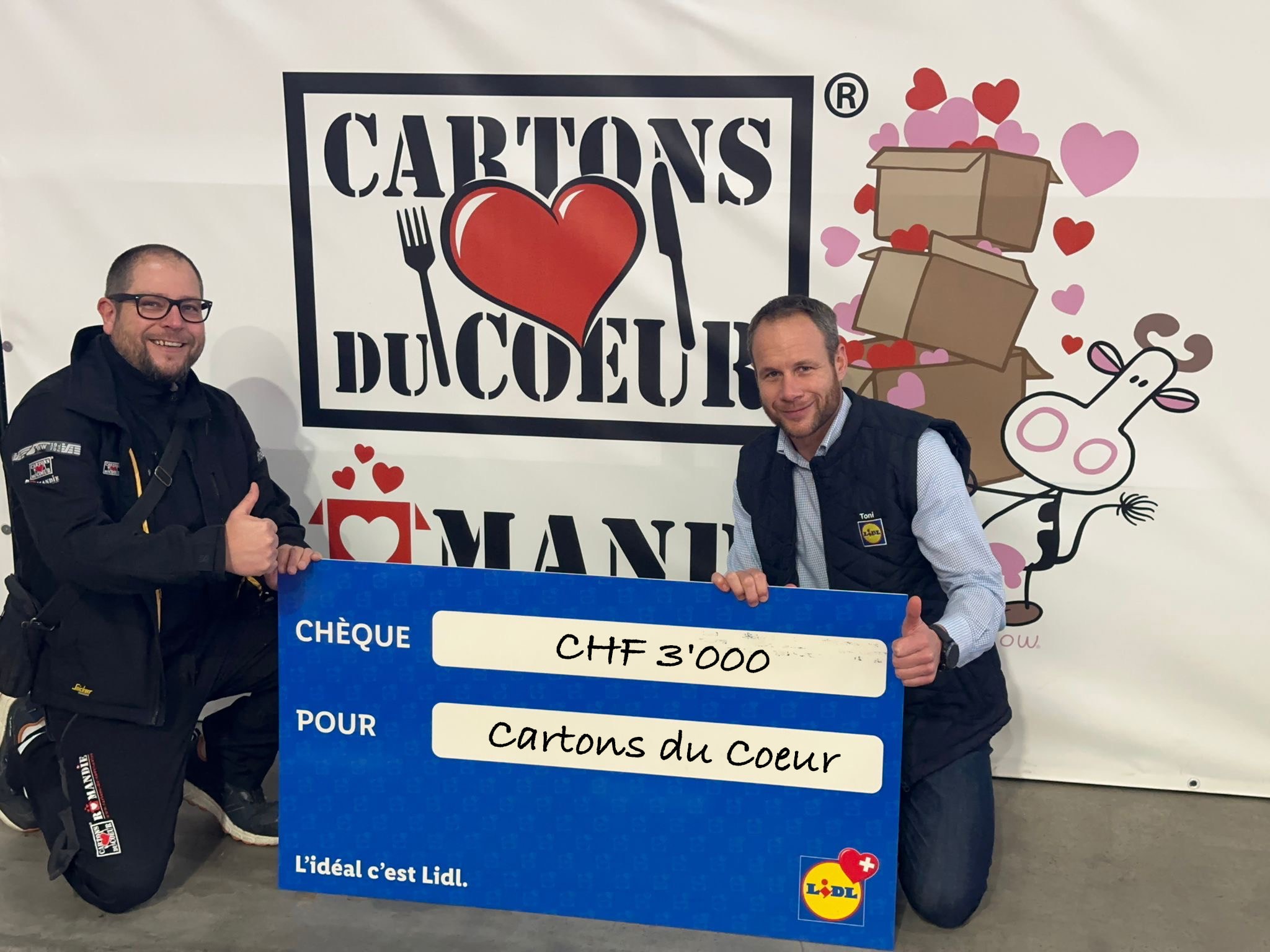 Übergabe eines blauen Schecks an Cartons du Coeur über einen Betrag von 3000 Franken.