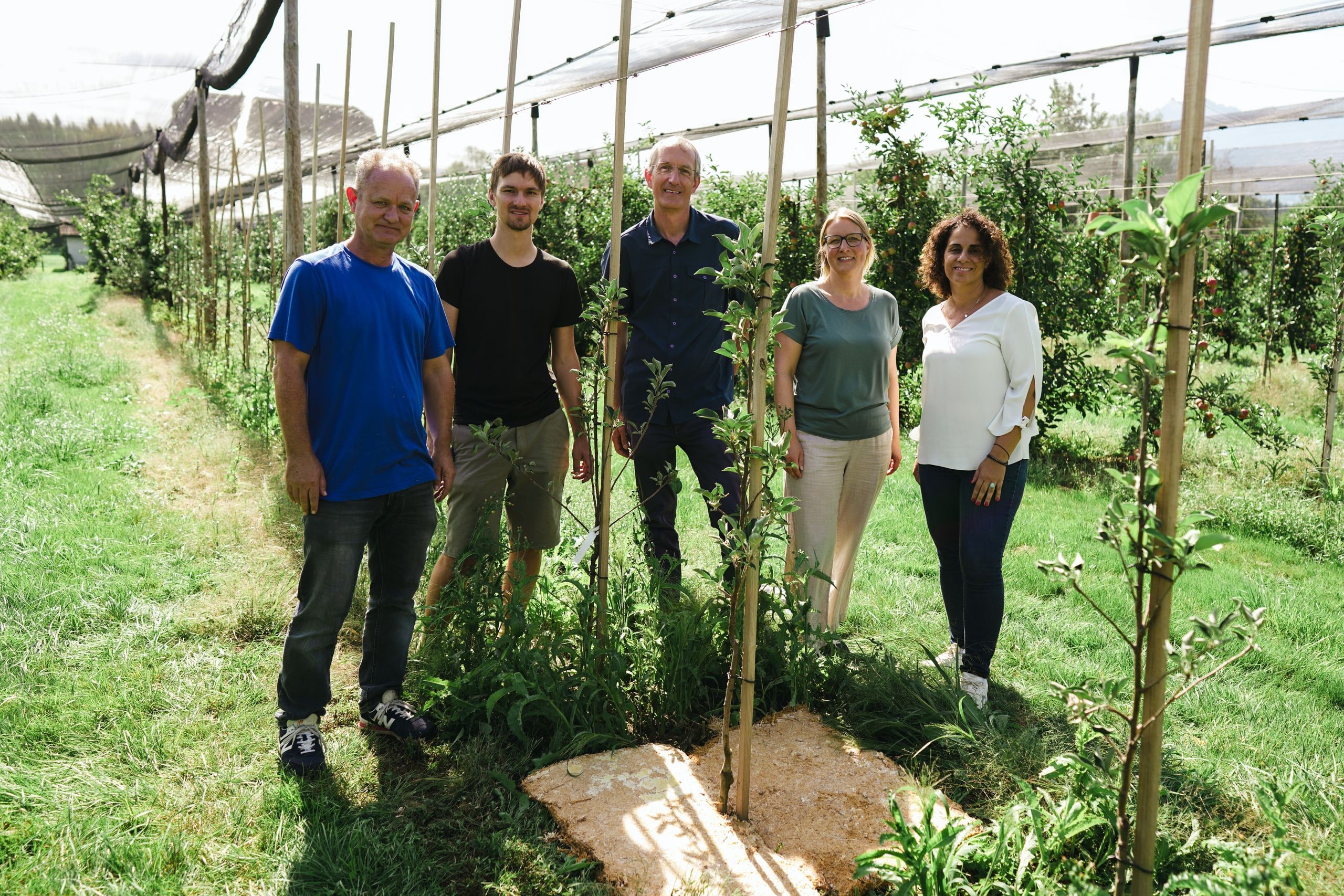 Das Myco-Mat-Projektteam von Lidl Schweiz und Partnern auf einer Obstplantage vor einer Pilz-Matte.