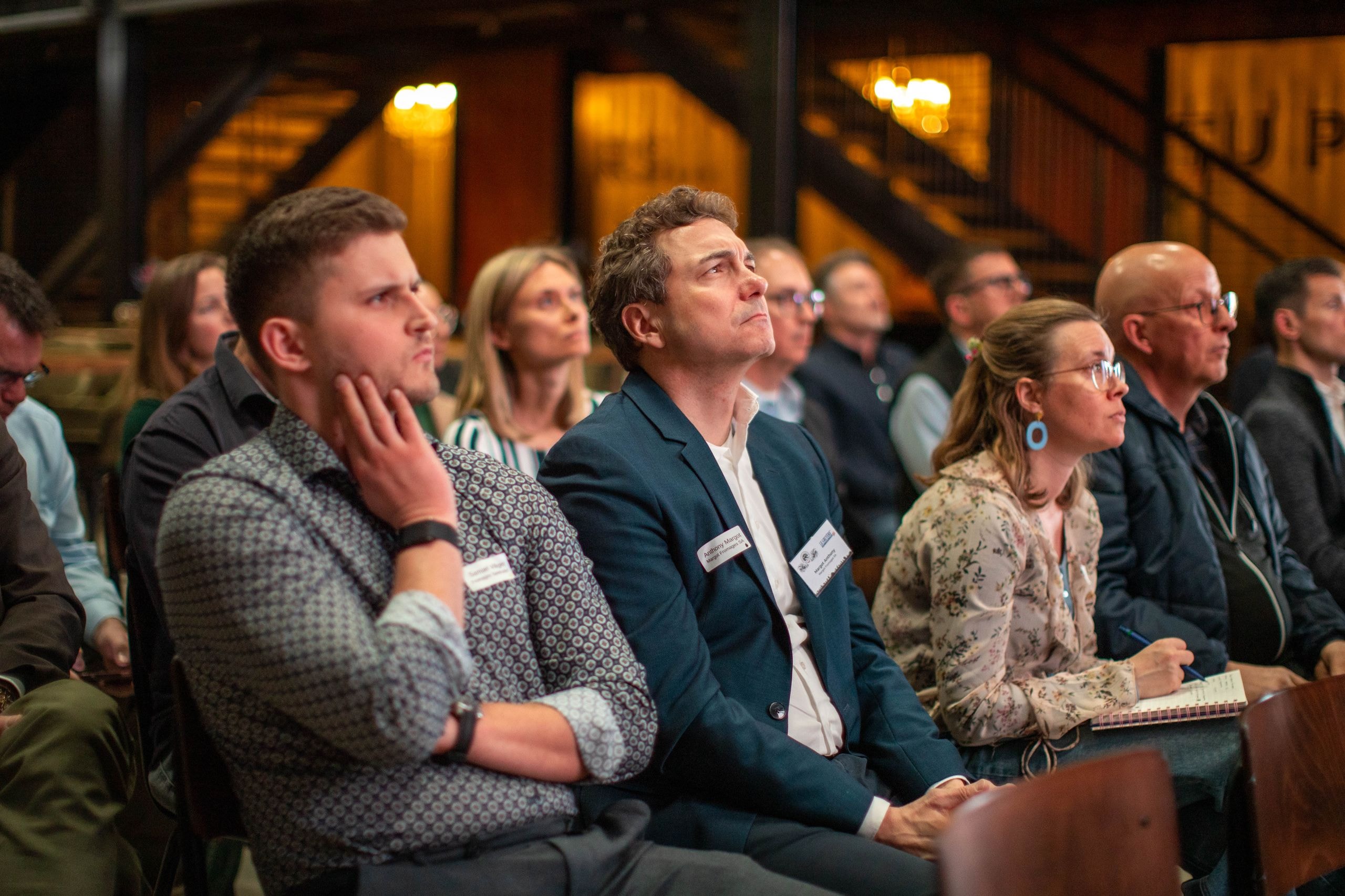 Aufmerksame Teilnehmende des Stakeholder-Dialogs verfolgen konzentriert die Präsentationen, einige machen sich Notizen.