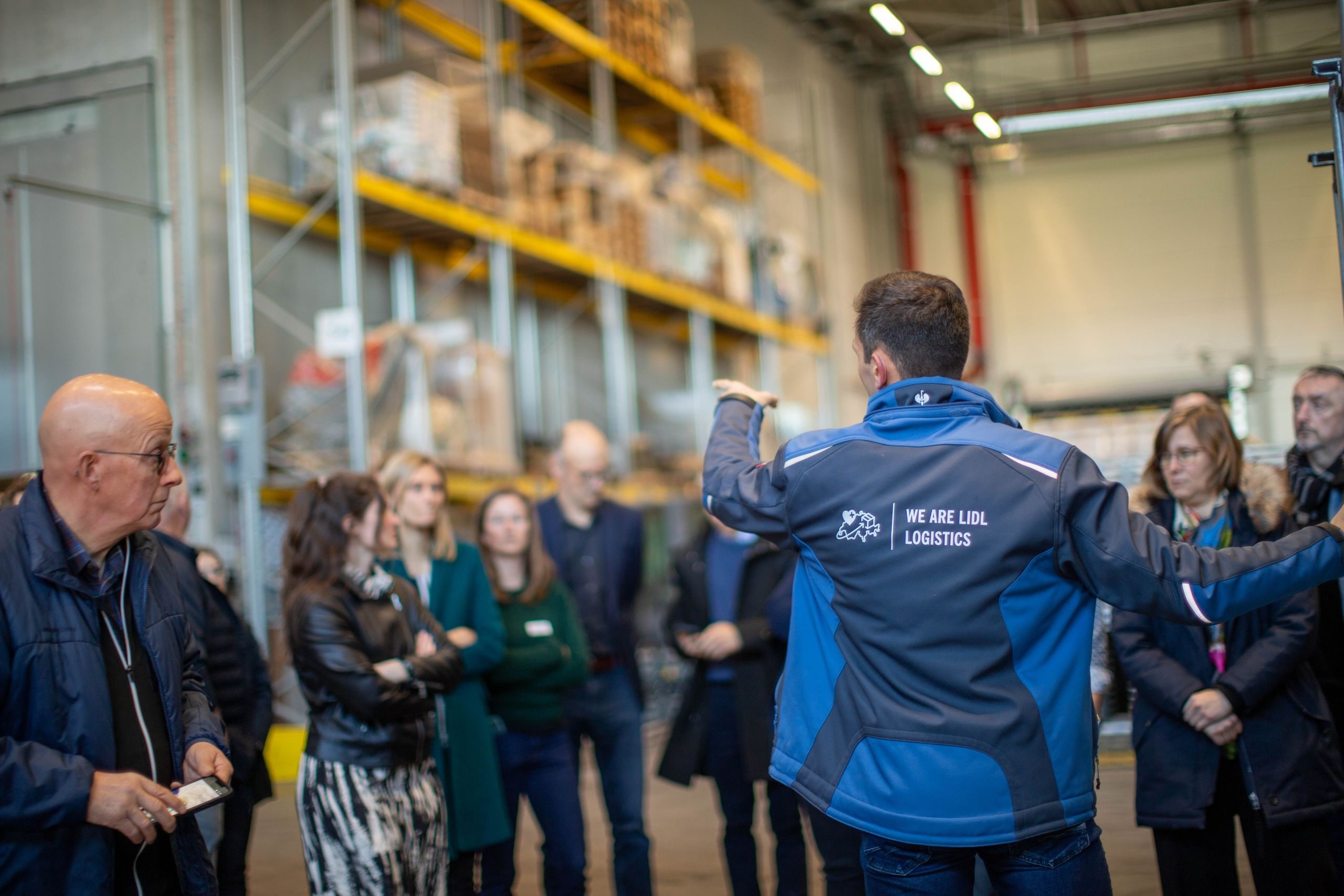 Un collaboratore di Lidl Logistics spiega ai visitatori i processi del centro logistico di Sévaz.