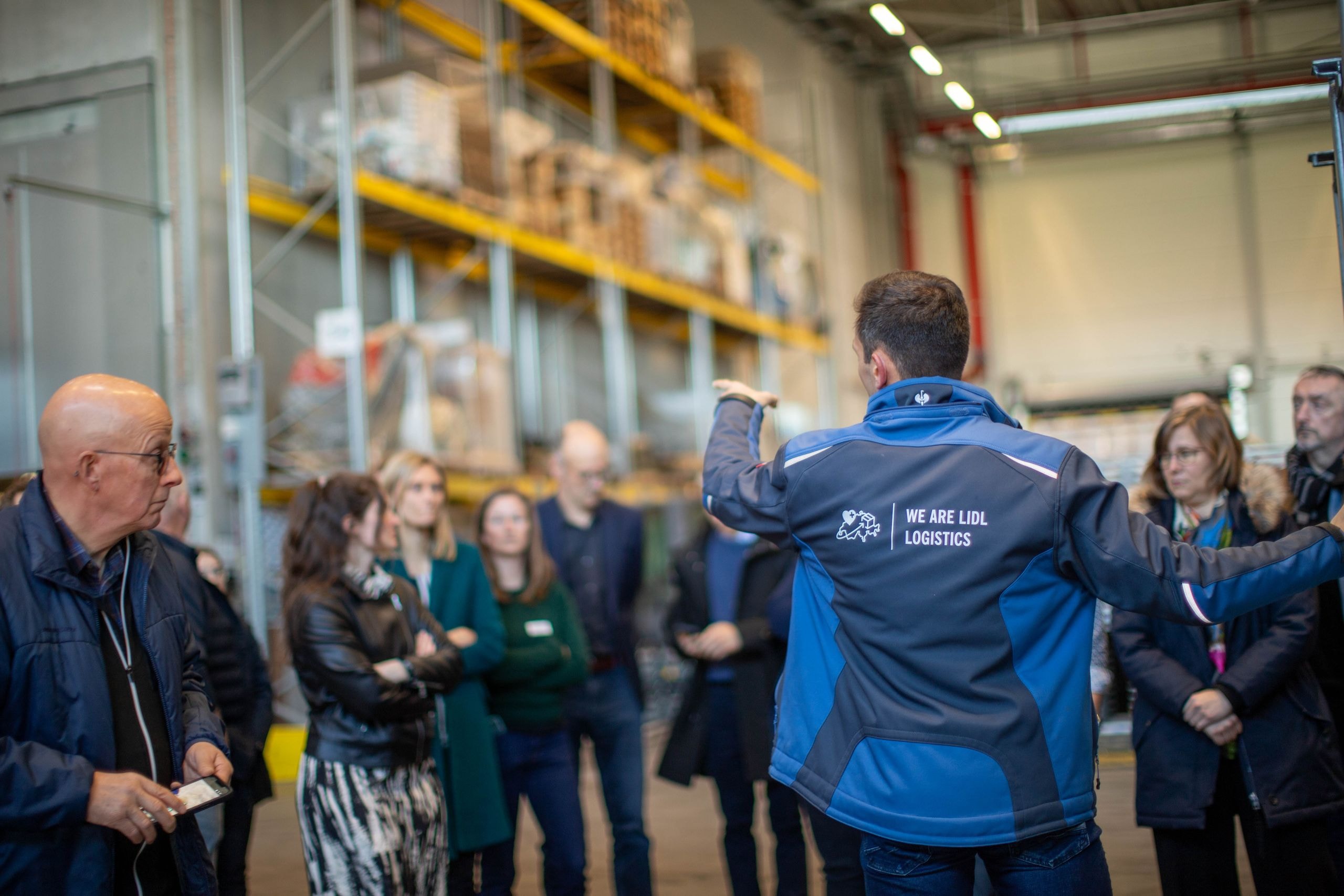 Ein Mitarbeiter von Lidl Logistics erklärt den Besuchenden die Abläufe im Logistikzentrum Sévaz.