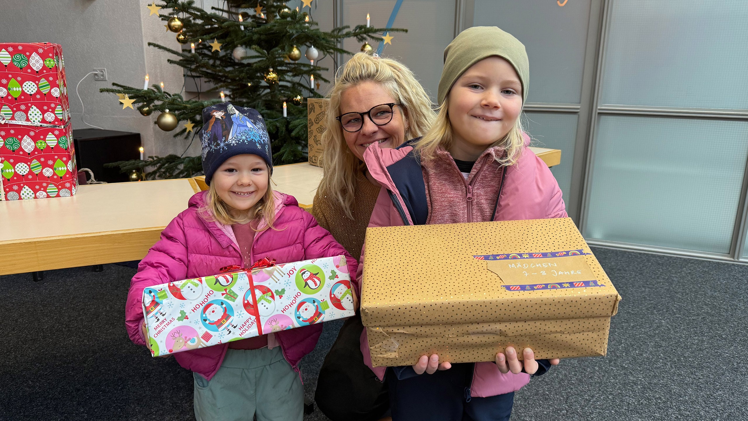 Anita Eichenberger avec deux enfants tenant des cadeaux de Noël.
