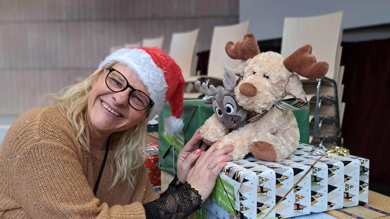 Anita Eichenberger de Petite Suisse Kinderhilfe avec deux rennes assis sur un cadeau.
