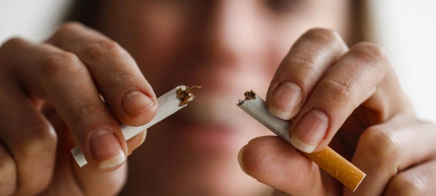 Sigaretta spezzata a fuoco, dita che ne tengono un pezzo ciascuna.
