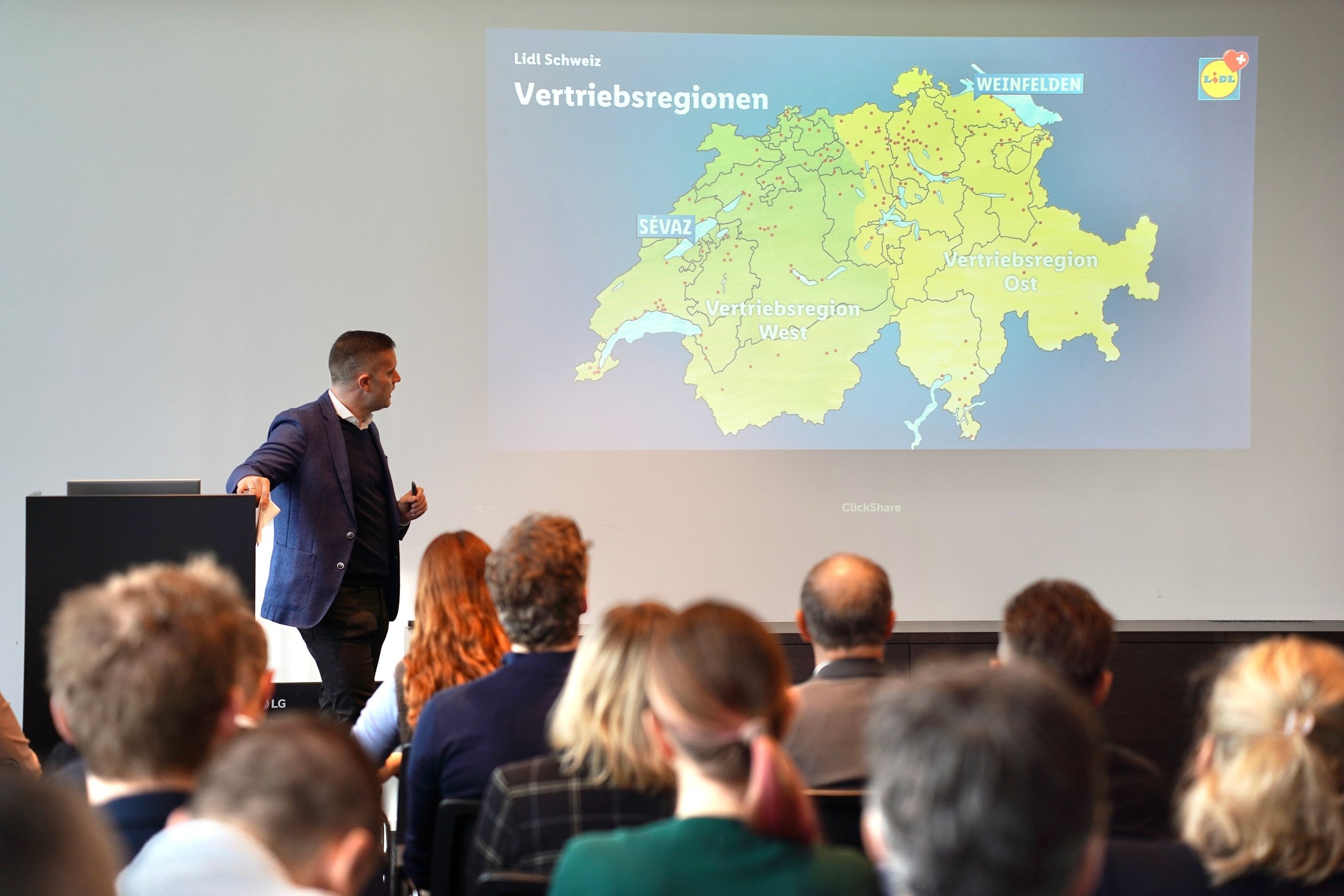 Le CEO de Lidl Suisse Nicholas Pennanen présente les régions de distribution suisses Ouest et Est avec les sites de Weinfelden et Sévaz devant des parties prenantes.